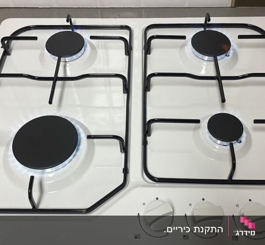 כיריים גז לבנות עם ארבעה מבערים דולקים